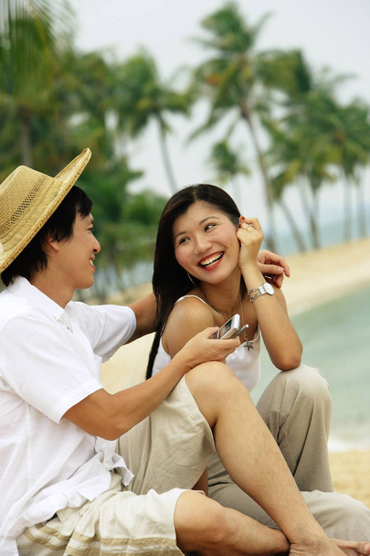 Couple on beach with mobile phone - Φωτογραφία, εικόνα