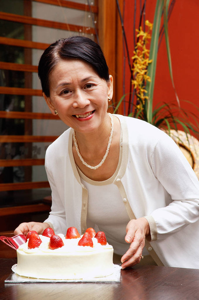 mature woman with birthday cake - 写真・画像