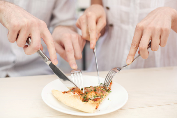 handen een plak van een pizza te snijden - Foto, afbeelding
