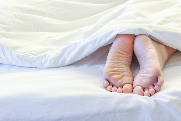 Feet of sleeping woman in white bed room  - Photo, Image