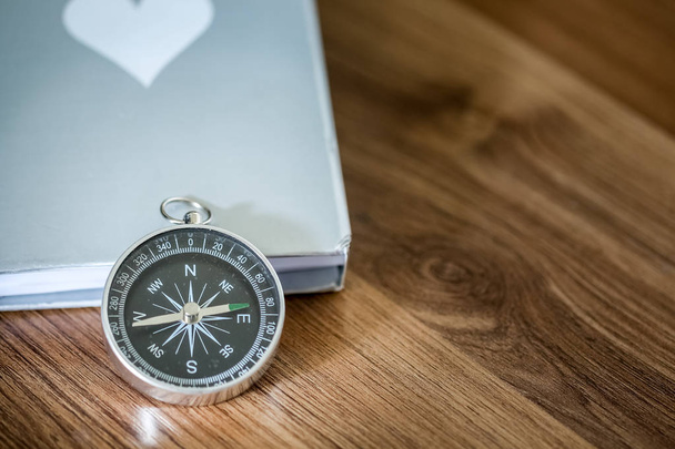 Simple compass over the book on the wooden table with copy space  - Φωτογραφία, εικόνα
