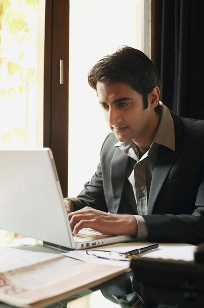 Liikemies työskentelee kannettavassa tietokoneessa
 - Valokuva, kuva