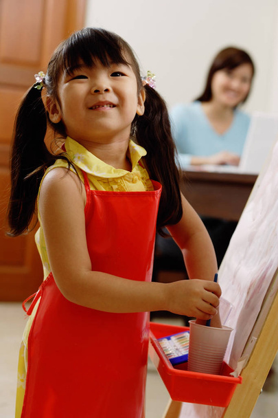 Young girl painting on easel - Foto, afbeelding