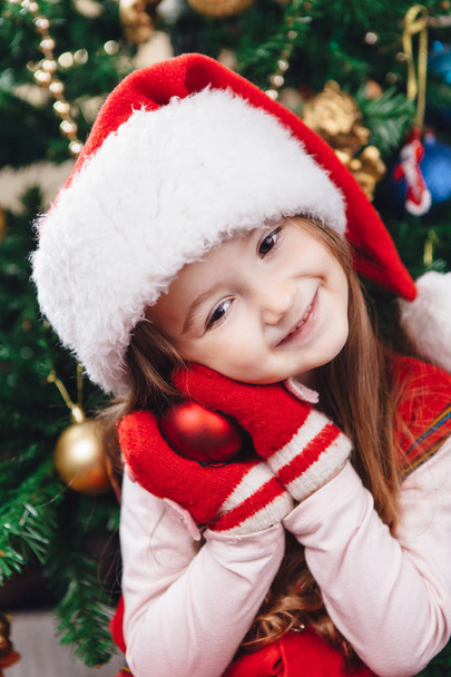 Smile girl in red hat hold a tree decoration - Foto, immagini