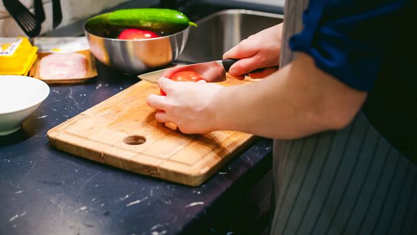 woman housewife in the kitchen. woman cuts vegetables, cooking, knife on a cutting board. Hands cooks close up - Foto, imagen