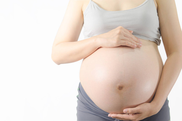 Close-up beeld van zwangere vrouw aanraken haar buik met handen o - Foto, afbeelding