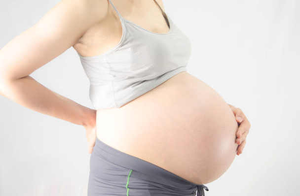 Mulher grávida com dor nas costas no fundo branco
 - Foto, Imagem