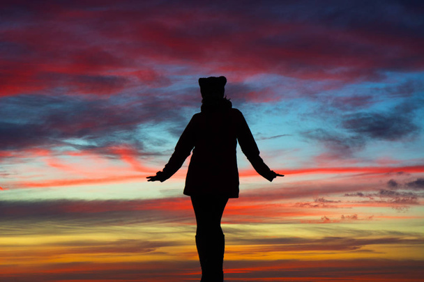 Silhouette einer Frau mit offenen Armen über dem atemberaubenden Himmel bei Sonnenuntergang. Freiheitskonzept - Foto, Bild