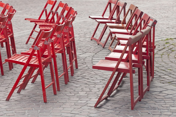 Червоні дерев'яні стільці на бруківці
 - Фото, зображення