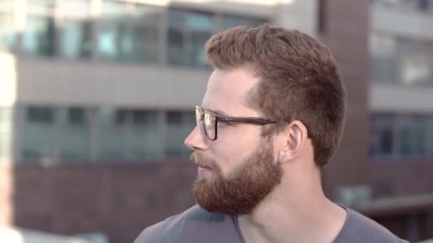 Portrait of young smiling handsome bearded men in glasses on industrial background - Video, Çekim