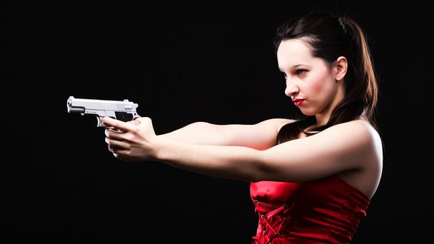 Sexy young woman - gun on black background - 写真・画像