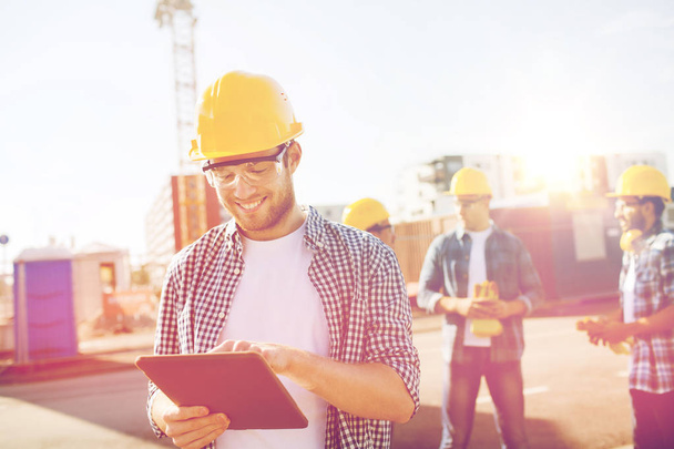 smiling builders in hardhats with tablet pc - Foto, Bild