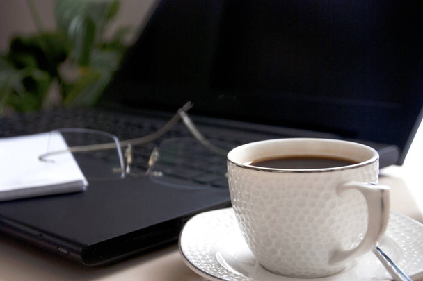 Bloco de notas em branco sobre laptop e xícara de café
.  - Foto, Imagem