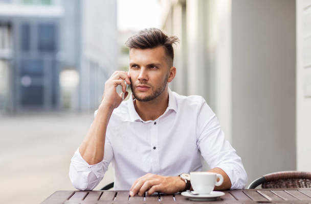 man with coffee calling on smartphone at city cafe - Valokuva, kuva