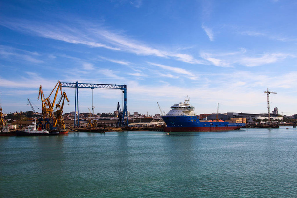 Táj nagy horgászcsónak vontatóhajó és daruk hajógyár a part Huelva, Andalúzia, Spanyolország. - Fotó, kép