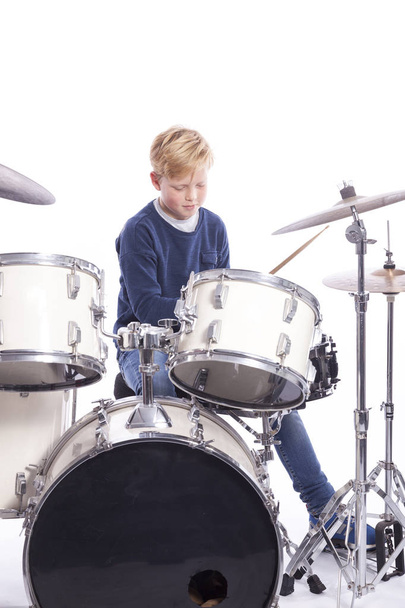 young caucasian boy at drum kit in studio plays music - Photo, Image