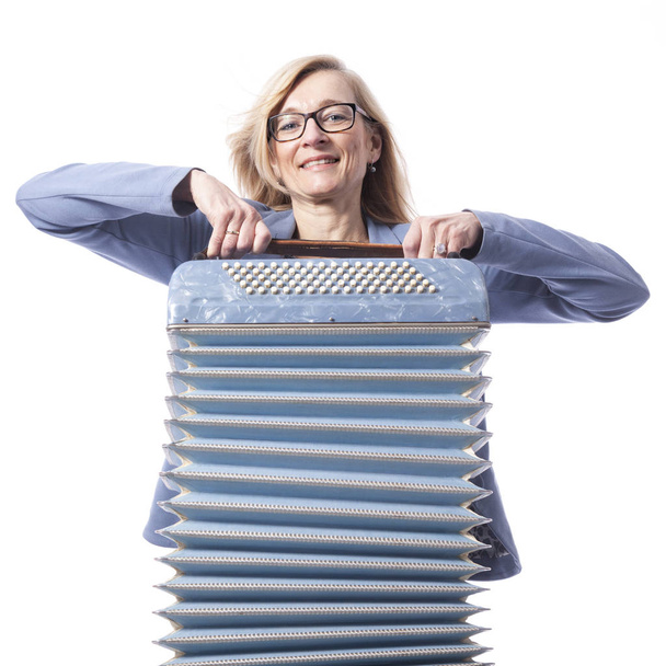 Kobieta w kolorze niebieskim z okularami trzyma akordeon i uśmiecha się - Zdjęcie, obraz