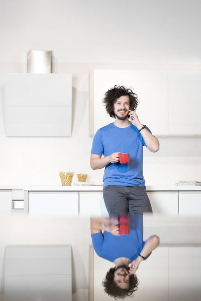 Man in kitchen using cell phone - Valokuva, kuva