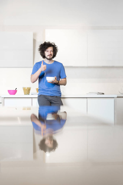 Man eating cereal in kitchen - Фото, изображение