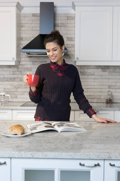 Woman drinking coffee in her kitchen - Zdjęcie, obraz