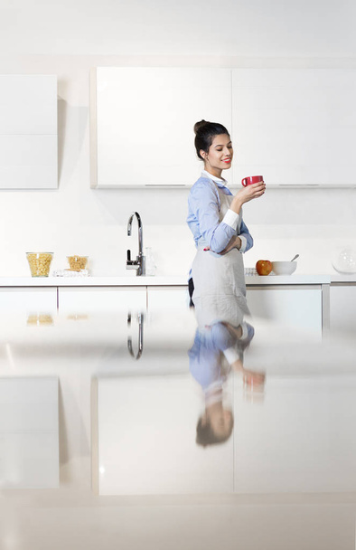 Woman drinking coffee in her kitchen - Fotoğraf, Görsel