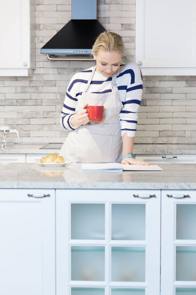 Woman drinking coffee in her kitchen - Fotó, kép