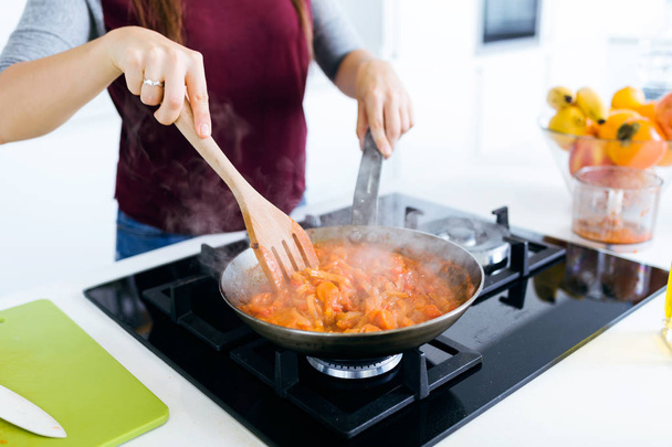 Young woman frying vegetables into the pan. - Foto, Bild