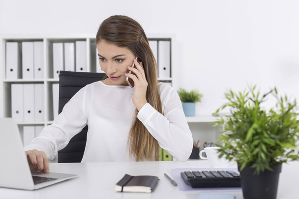 Woman in white office on her phone - Foto, Bild