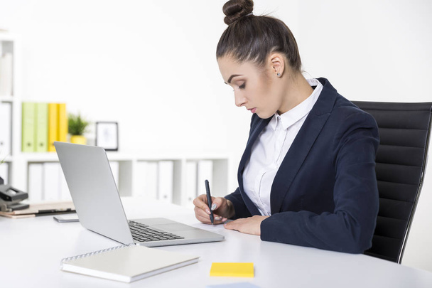 Serious businesswoman is writing a note - Foto, Imagen