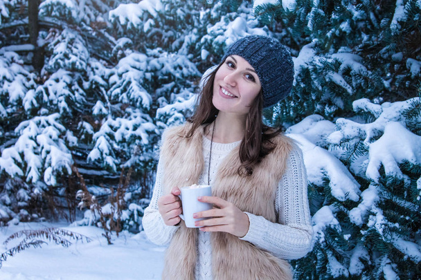 Mujer sostiene taza de café con malvavisco en el bosque de invierno
 - Foto, imagen
