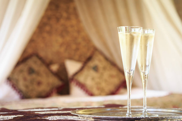 Due bicchieri di champagne con letto a baldacchino orientale sullo sfondo
 - Foto, immagini
