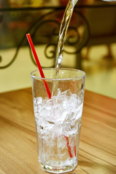highball glass with ice and a red tube on the wooden bar - Photo, Image