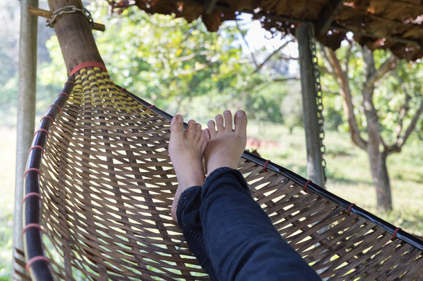 ноги жінки відпочивають, розслабляються, сплять на ротанговій колисці в га
 - Фото, зображення