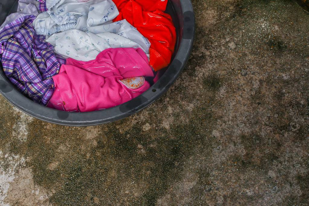 Mergulhe roupas sujas na bacia preta para limpar
 - Foto, Imagem