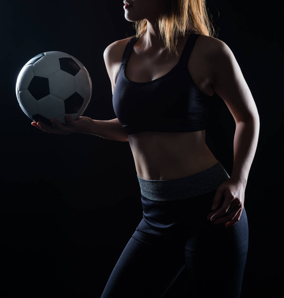 Mooie vrouw met een voetbal zwarte achtergrond - Foto, afbeelding