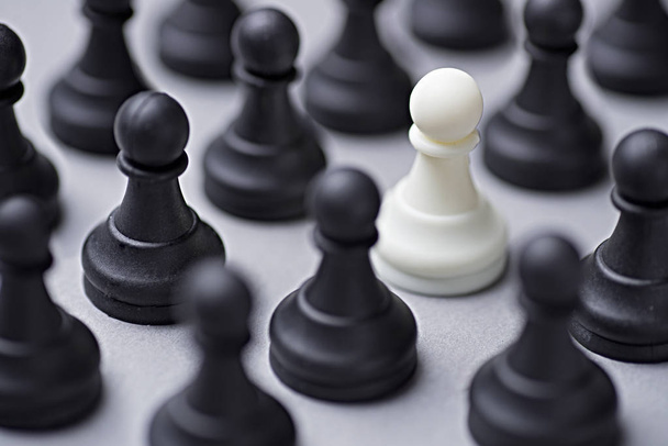 Pojedynczy biały szachy pawn wśród czarne - Zdjęcie, obraz