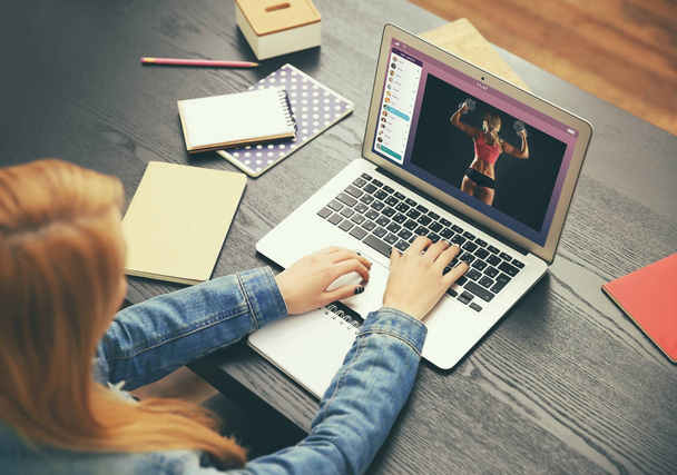 Kobieta oglądająca treningi sportowe online na laptopie. Blog fitness i sport. - Zdjęcie, obraz