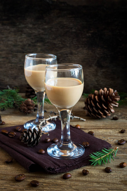 Irish cream coffee liqueur with coffee beans, Christmas decoration and cones over rustic wooden background - homemade festive Christmas alcoholic drink - Foto, afbeelding
