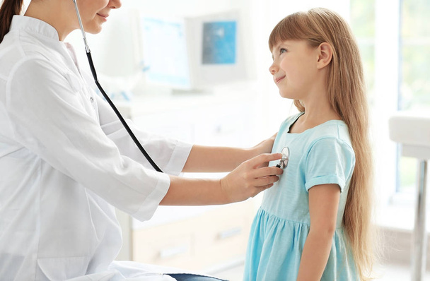 Pediatrician examining little girl's heart - 写真・画像