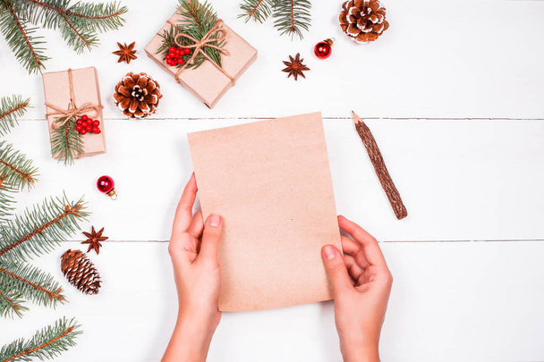 Noel hediyeleri, çam dalları, çam kozalakları, kırmızı süslemeleri tatil zemin üzerine Noel Baba'ya bir mektup okuma ve yazma el. Noel ve mutlu yeni yıl kompozisyon. Düz yatıyordu, en iyi görünümü - Fotoğraf, Görsel