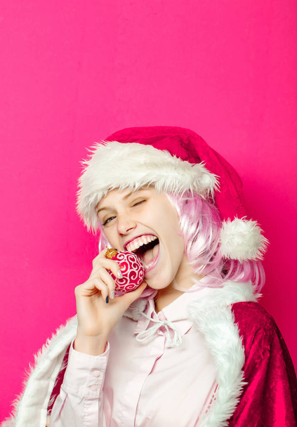 Winking girl bites Christmas bauble - Фото, изображение