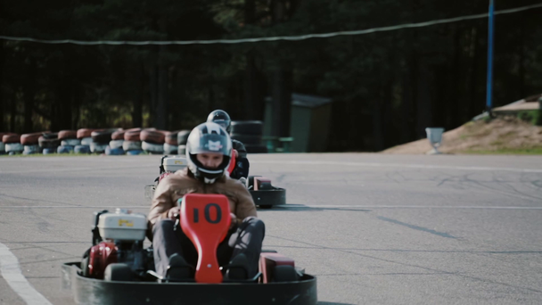 Kart drivers moving on a go kart track passing by the camera. - Footage, Video