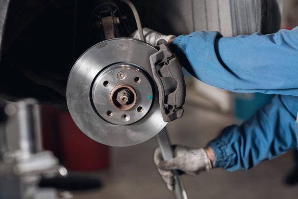 change the old drive to the Brand new brake disc on car in a garage. Auto mechanic repairing . - Valokuva, kuva