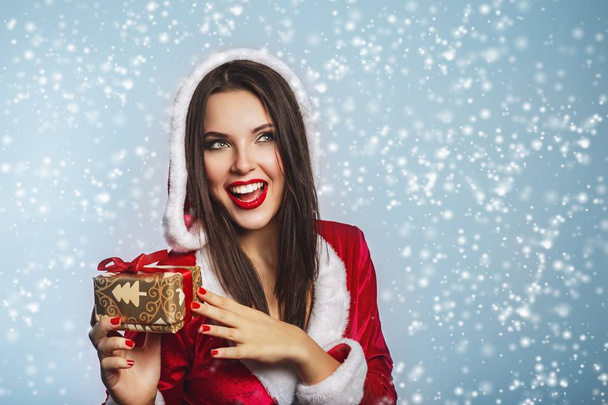 Christmas Santa hat woman portrait hold christmas gift boxs. Smiling happy girl on blue background.Portrait of beautiful sexy girl wearing santa claus clothes - Foto, Imagen