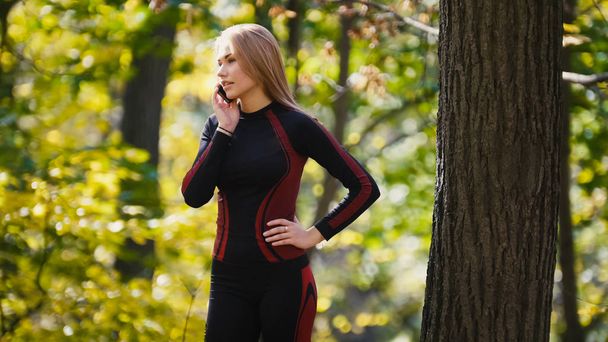 Giovane donna sportiva che parla al cellulare al parco autunnale all'aperto, da vicino
 - Foto, immagini