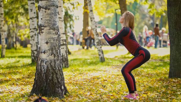 Szexi vonzó női szőke bikini-fitness modell nyújtás a földön őszi parkban tartozó sárga levelek - sport guggolás - Fotó, kép
