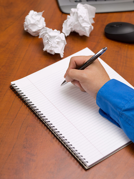 Close up shot of a person writing on spiral notepad on desk - Photo, Image