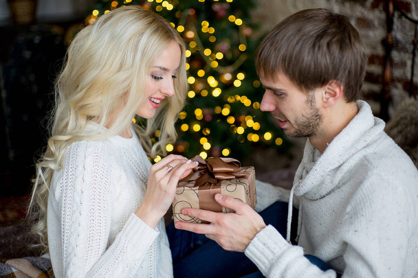 Happy couple of lovers in white pullovers give each other gifts - Foto, afbeelding