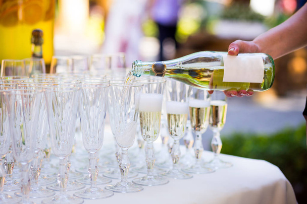 Le serveur verse du champagne dans un verre.Verres vides sur la table blanche, Une rangée de verres à champagne vides.Furshet, traiteur.Verres pour champagne ou vin
. - Photo, image