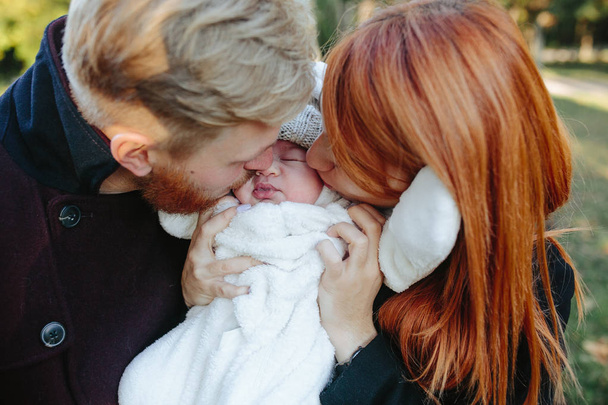 молодая семья и новорожденный сын в осеннем парке
 - Фото, изображение